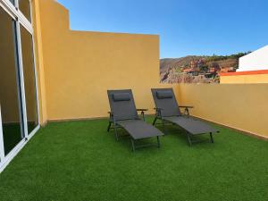 three chairs on a balcony with green grass at Sardina Beach Retreat in Gáldar