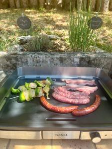 a grill with sausages and vegetables on it at Le Petit Manoir avec Piscine Privée in Le Bugue