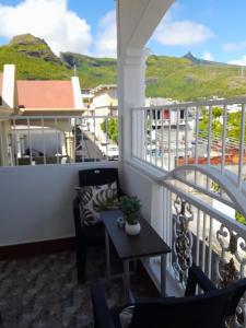 a balcony with a table and chairs and mountains at Vue de Vallee in Port Louis