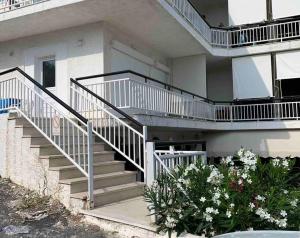 a building with stairs and flowers in front of it at Veranda Agia Marina in Agia Marina Aegina