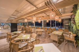 a restaurant with wooden tables and chairs and plants at Les Dunes Comodoro in Benidorm