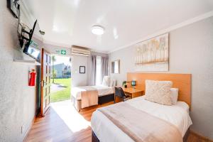 a bedroom with two beds and a desk and a tv at 16 Vaalrivier in Secunda