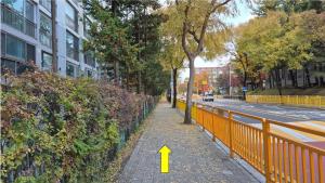 a yellow arrow pointing down a sidewalk next to a fence at Nick's home01 in Ilsan-ni