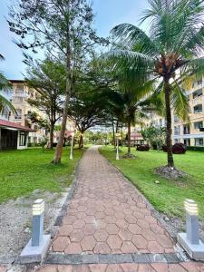 a path in a park with palm trees and buildings at Tiara Homestay Desaru - Garden Pool View in Bandar Penawar