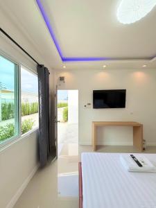 a bedroom with a bed and a tv on the wall at โรงแรม นีโอ รีสอร์ท in Ban Thap Nang