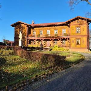 a large wooden house with a statue in front of it at Modrzewiowy Dworek in Mirzec +43 photos