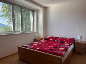 a bedroom with a bed with red sheets and a window at Penzión Terno in Považská Bystrica