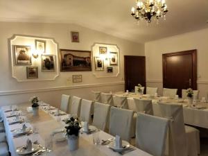 a room with white tables and white chairs and a chandelier at Modrzewiowy Dworek in Mirzec