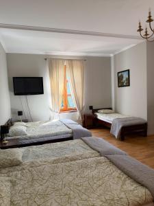 a bedroom with two beds and a flat screen tv at Modrzewiowy Dworek in Mirzec