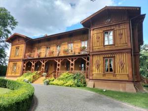 a large wooden house with a porch and a driveway at Modrzewiowy Dworek in Mirzec