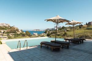 a swimming pool with benches and umbrellas next to a pool at Villa Mononaftis in Agia Pelagia