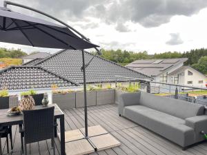 a patio with a couch and a table and an umbrella at #NEU l Seeblick l NETFLIX l BOXSPRING l NESPRESSO l e-TÜR l Terrasse l 82m2 in Ulmen