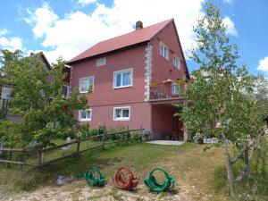 a pink house with a fence and a yard at Apartmani Sobe Šljivančanin in Žabljak