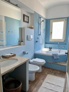 a blue bathroom with a toilet and a tub and a sink at Giué in Bovalino Marina +28 photos