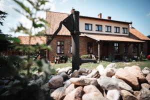 a house behind a pile of rocks in front of a house at Agroturystyka Czułe Miejsce in Zdory