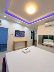 a bedroom with a white bed and a flat screen tv at โรงแรม นีโอ รีสอร์ท in Ban Thap Nang +6 photos