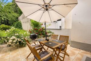 ein Holztisch mit Sonnenschirm auf einer Terrasse in der Unterkunft MOLA Apartments-Stilvolle Altstadtwohnung- Seilersee-5 Personen-Terrasse-Grill-Gratis WLAN in Iserlohn