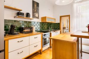 Eine Küche mit weißen Schränken und grünen Fliesen in der Unterkunft MOLA Apartments-Stilvolle Altstadtwohnung- Seilersee-5 Personen-Terrasse-Grill-Gratis WLAN in Iserlohn