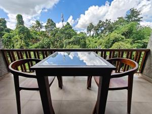 a glass table and two chairs on a balcony at Nawang Sakti in Ubud
