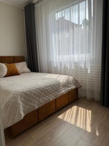 a bed in a bedroom with a large window at Golden corner in Plungė +10 photos