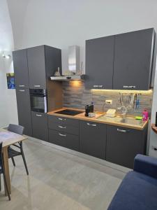 a kitchen with grey cabinets and a sink and a table at Casa Vacanza S Elia in Veglie