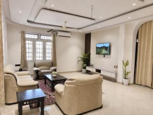 a living room with a couch and chairs and a tv at Private Farm with Big Size Pool & 7 Rooms in Kukas in Jaipur