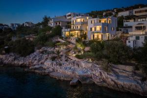 a house on a cliff near the water at night at Villa Lavanda Deluxe in Rogoznica
