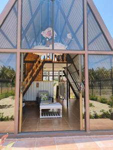 a glass house with a staircase and a bench at A-frame cabin in Parrita