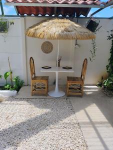 a table and two chairs under a straw umbrella at A-frame cabin in Parrita