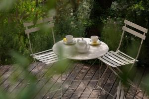 a white table with two chairs and two cups and saucers at Villino con piscina in Terni +19 photos