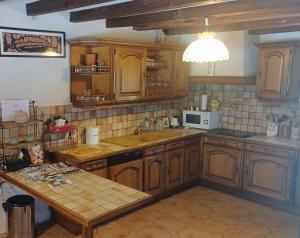 a kitchen with wooden cabinets and a sink and a table at Le Gîte du Vauvril in Saint-Usuge +27 photos