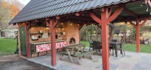 a pavilion with a table and benches in a park at Folwark Pod Bukowcem in Podzamcze