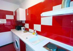a red and white bathroom with a sink and a washing machine at Harmony Rooms & Studios in Constanţa +48 photos