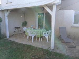 a table and chairs under a white pergola at Villa climatisée 4-6 pers avec piscine, terrasse & jardin - 2 min plage in Cervione