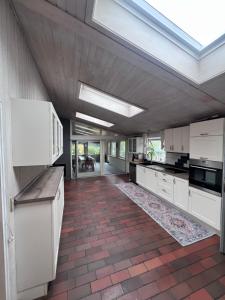 a large kitchen with white cabinets and a skylight at Sommerhus in Grevinge