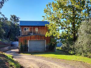 a wooden house with a garage on a dirt road at The Shed House in Mount Beauty