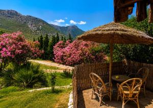 a table and chairs with an umbrella and flowers at Caiat Lounge Refuge , Mountain Lodge near Akchour Waterfalls in Taghzoute