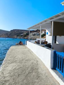 a dog sitting on a dock next to the water at Onar Sifnos by the sea in Cherronisos