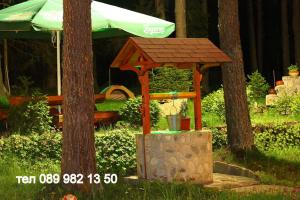 a wooden gazebo in a park with a bench at Вила Шишарка in Govedartsi
