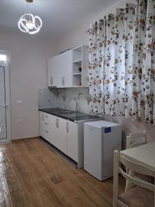a kitchen with white cabinets and a table at Sunset Bliss Apartments in Sarandë