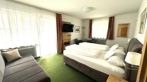 a bedroom with a large bed and a couch at Hotel Steffl Garni inkl Chiemgau Karte in Ruhpolding