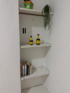 three yellow vases sitting on shelves with books at Apartamento individual in Ipatinga