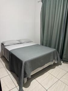 a bed in a room with green curtains at Apartamento individual in Ipatinga