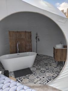 a bathroom with a tub and a sink and a mirror at La Bulle des Brosses étoilées in Igé