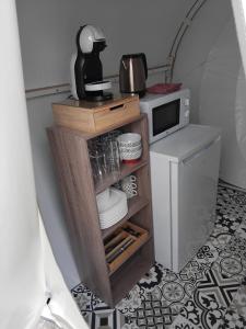 a small kitchen with a shelf with plates and a microwave at La Bulle des Brosses étoilées in Igé