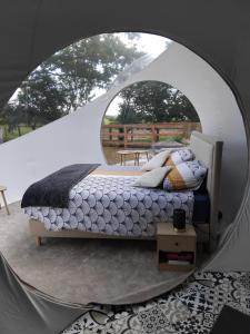 a bedroom with a bed in a round mirror at La Bulle des Brosses étoilées in Igé