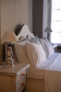 a bed with white sheets and a lamp on a nightstand at "LOS" 1 Neoclassic Harbour View in Symi