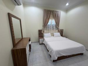 a bedroom with two beds and a mirror and a window at شقق ذاعذاع النسيم المخدومة in Al Khuraymī