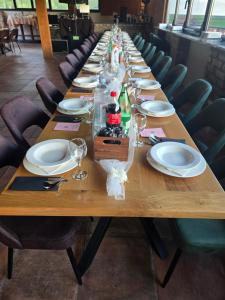 a long wooden table with plates and wine glasses at Kopićland HOMES in Marinci +8 photos