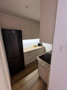 a kitchen with a black refrigerator and a wooden floor at Zamkowa18 in Pabianice